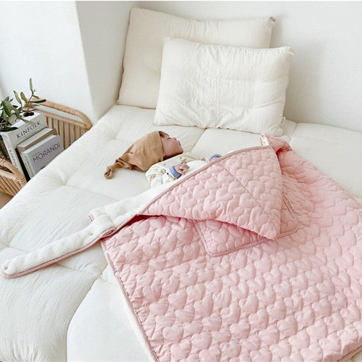 couverture de portage douillette recouvrant bébé sur le lit